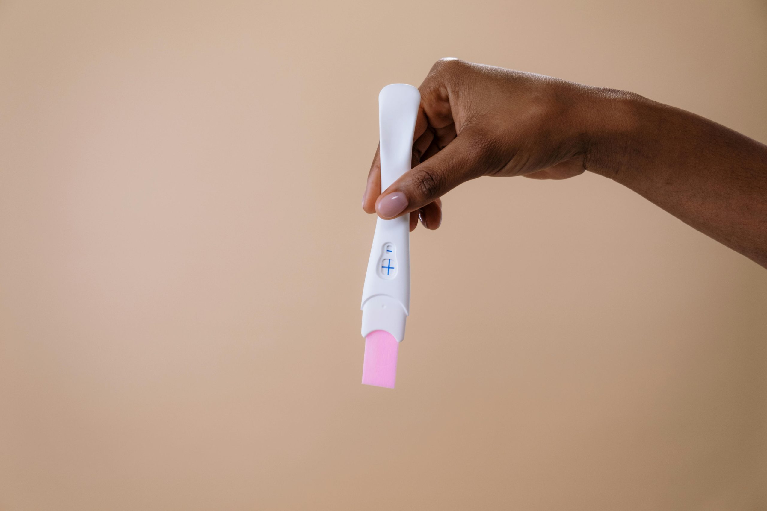 Hand holding positive pregnancy test